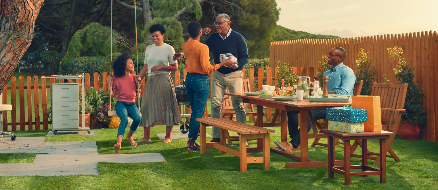 Actor portrayals of family eating at a picnic table in their backyard